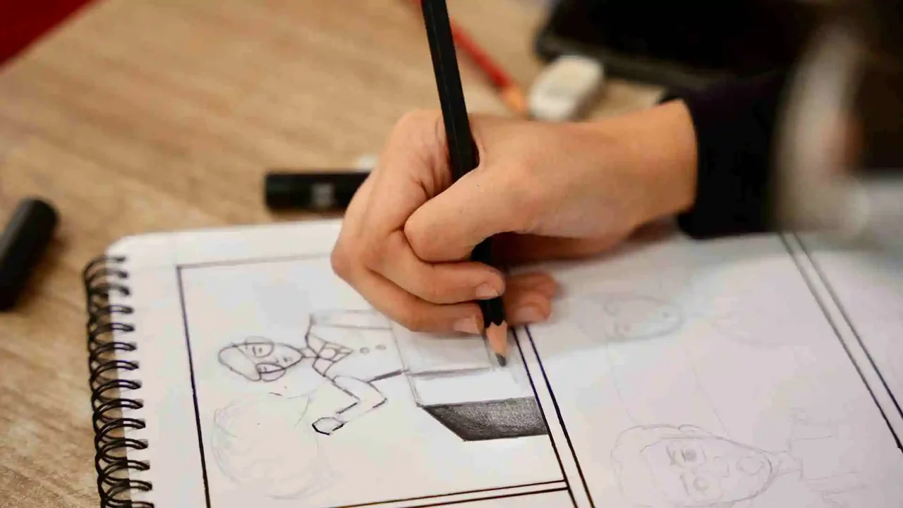 Close-up of a hand sketching characters in a spiral-bound comic notebook