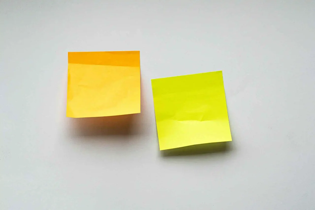 Orange and yellow sticky notes placed side by side on a white surface
